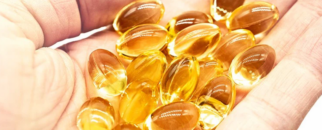 A hand holding multiple CBD gel capsules, showcasing their size and color.