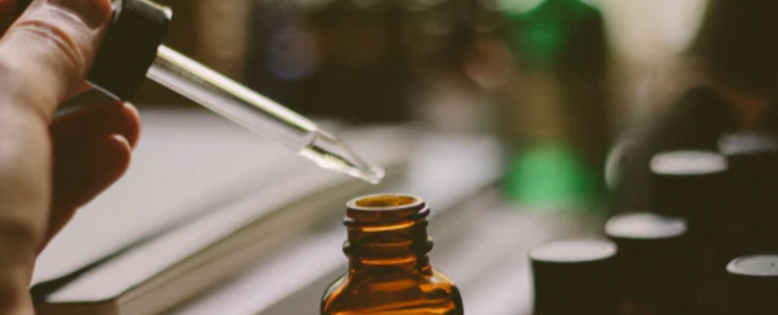 A dropper dispensing organic CBD oil from a brown glass bottle