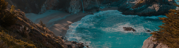 A tranquil coastal scene with turquoise water, sandy beach, and a waterfall.