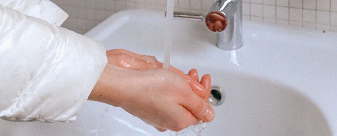 Person washing hands under running water at a sink