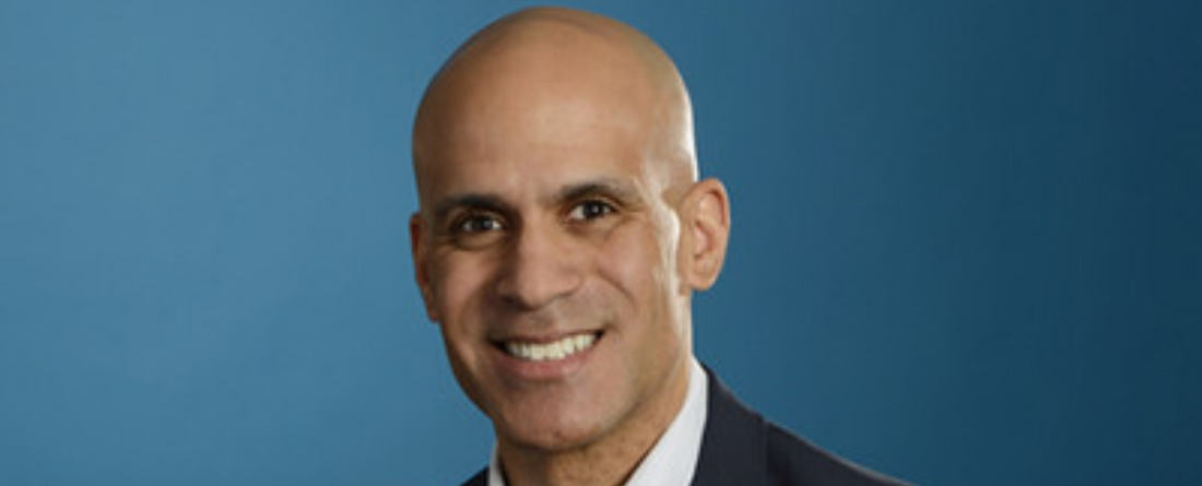 Medterra’s new CEO smiling in a suit against a blue studio background