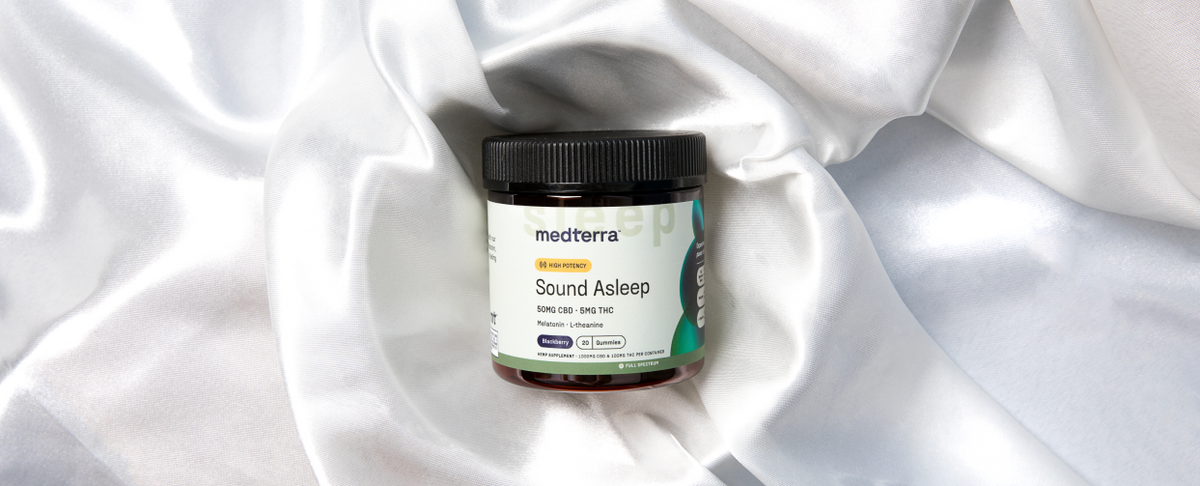 Front view of Medterra Sound Asleep gummies jar showing black screw-top lid and product label on white silky fabric