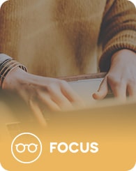 Person in a brown sweater using a tablet with a yellow gradient overlay. The word "FOCUS" and an icon of glasses are at the bottom.