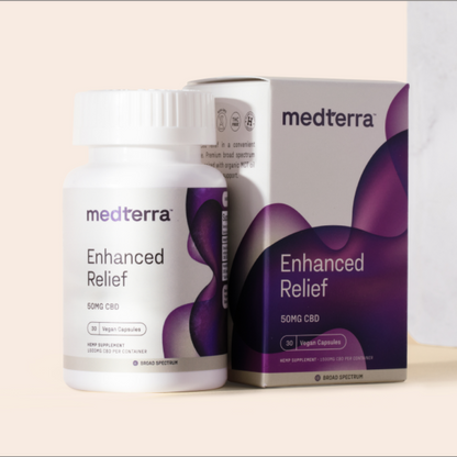 A bottle and box of Medterra Enhanced Relief Broad Spectrum Capsules, showcasing "50MG CBD" and "Vegan Capsules." The white container with a purple abstract design prominently features the brand name "Medterra." This product utilizes Broad Spectrum CBD. The background is a neutral beige.