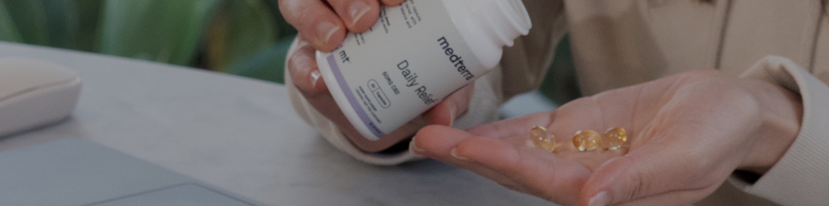 Hands pouring golden softgel capsules from a medterra Daily Relief bottle into an open palm