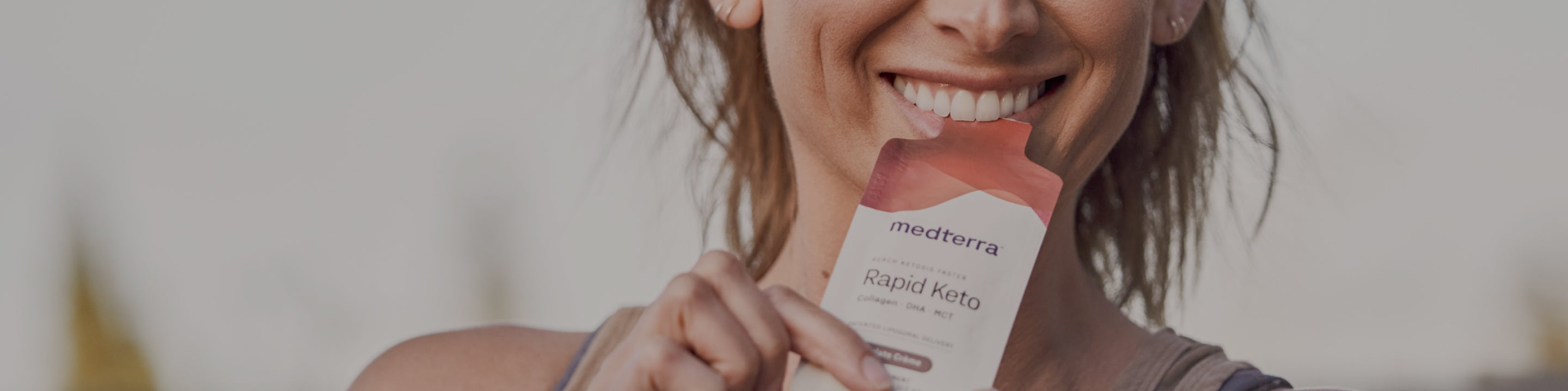 Smiling woman holding a medterra Rapid Keto sachet near her mouth; packaging text reads Collagen DHA MCT