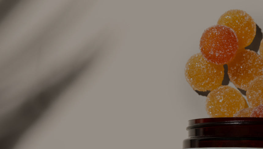 Medterra round orange‑red gummies floating above a brown jar against a blurred gray background.