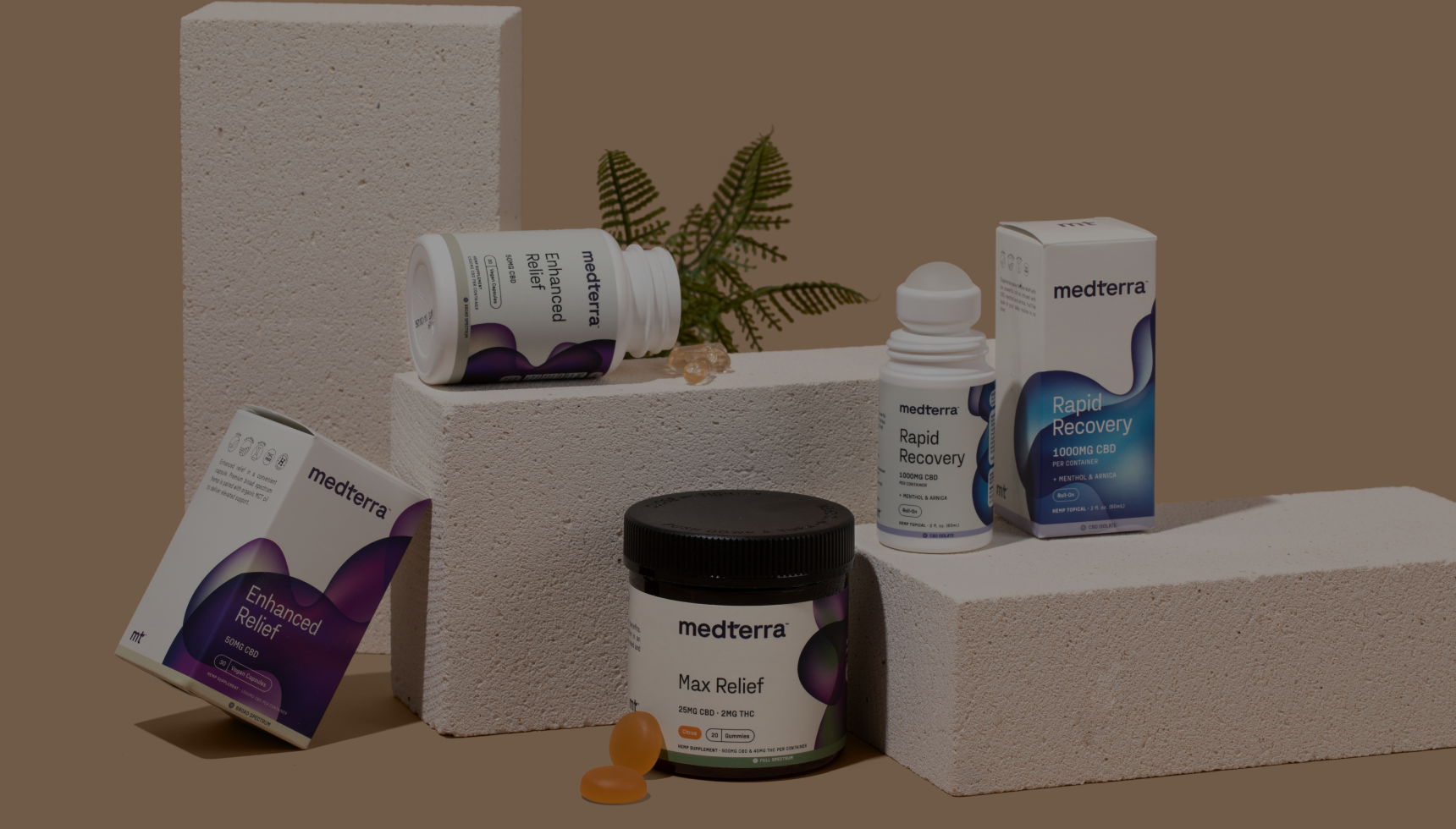 Medterra CBD products on textured blocks: Max Relief jar, Enhanced Relief box (50MG CBD), and Rapid Recovery roll-on (1000MG CBD).