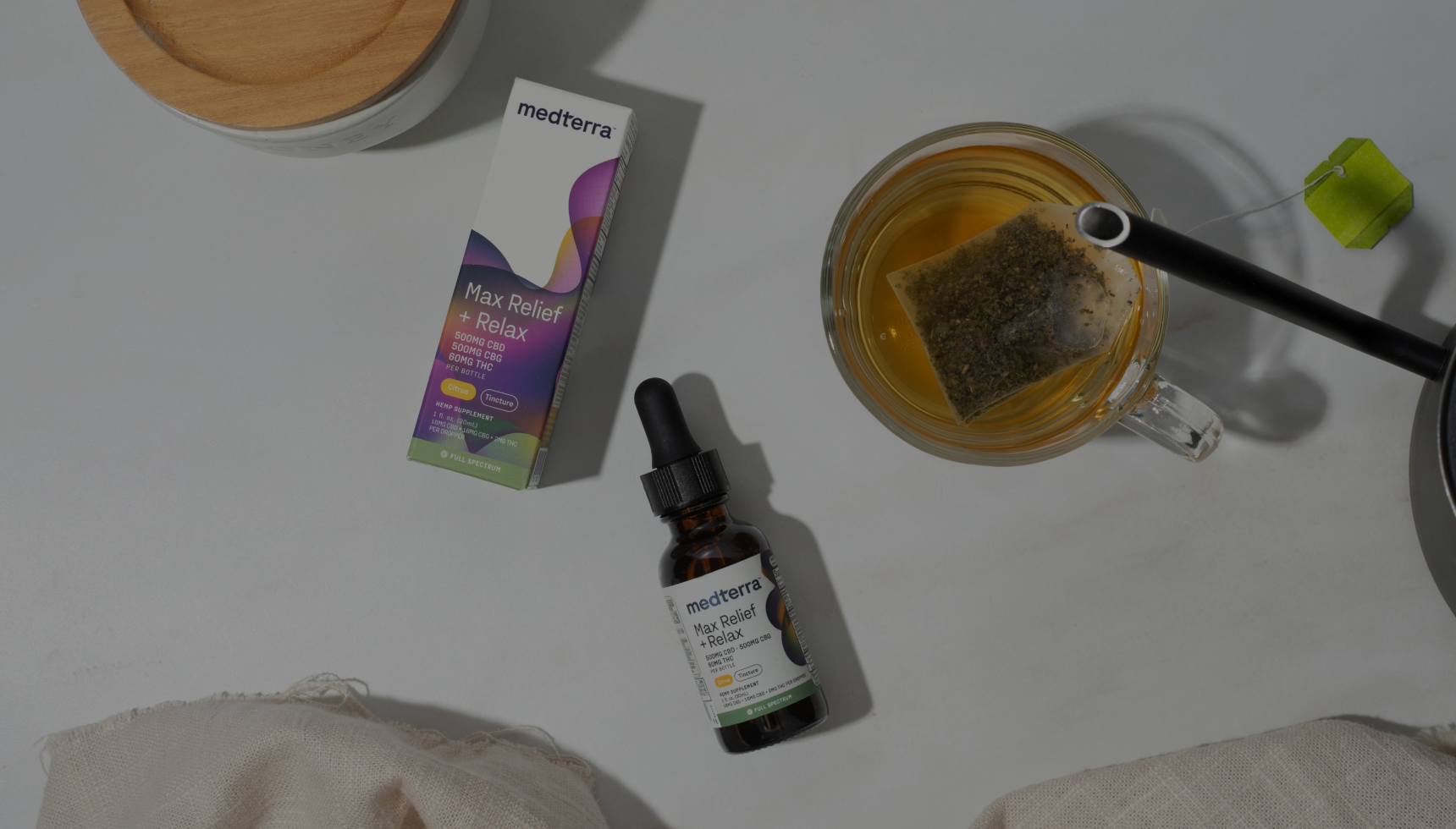 medterra Max Relief + Relax tincture bottle and box labeled Citrus, Full Spectrum, beside a cup of tea with tea bag.