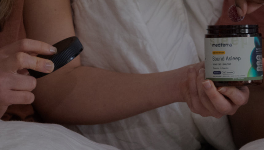 Hands holding a jar labeled 'medterra Sound Asleep' near a bed, one hand removing the black lid