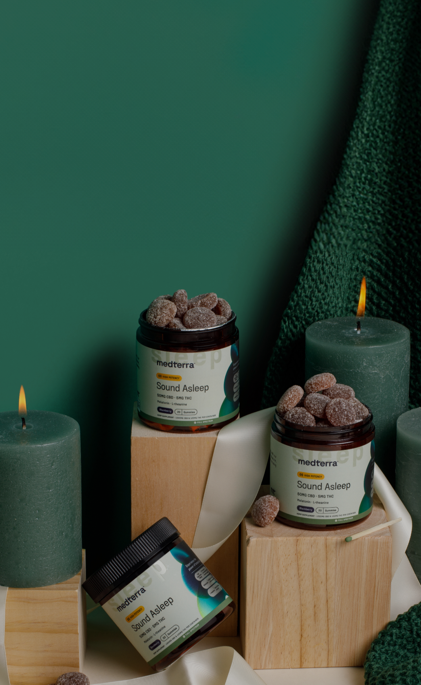medterra Sound Asleep 50MG CBD - 5MG THC Gummies jars styled with green candles and wooden blocks